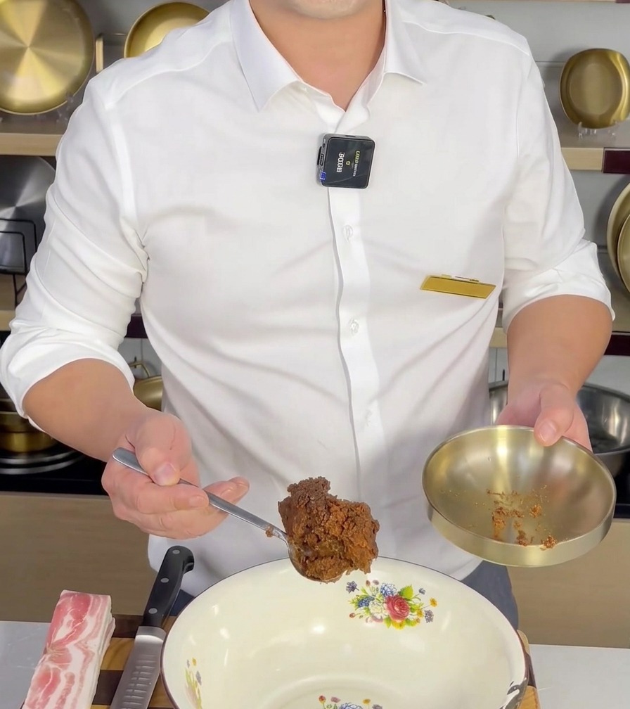 Ein Löffel Doenjang wird in eine weiße Rührschüssel gegeben, um mit anderen Zutaten vermischt zu werden.