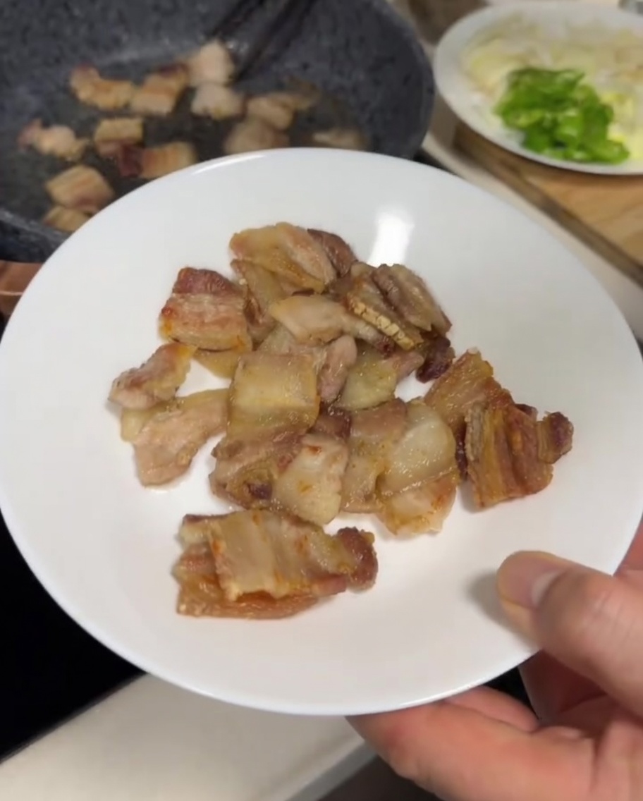 Schweinebauchscheiben in einer grauen Pfanne, die außen goldbraun und leicht knusprig sind.
