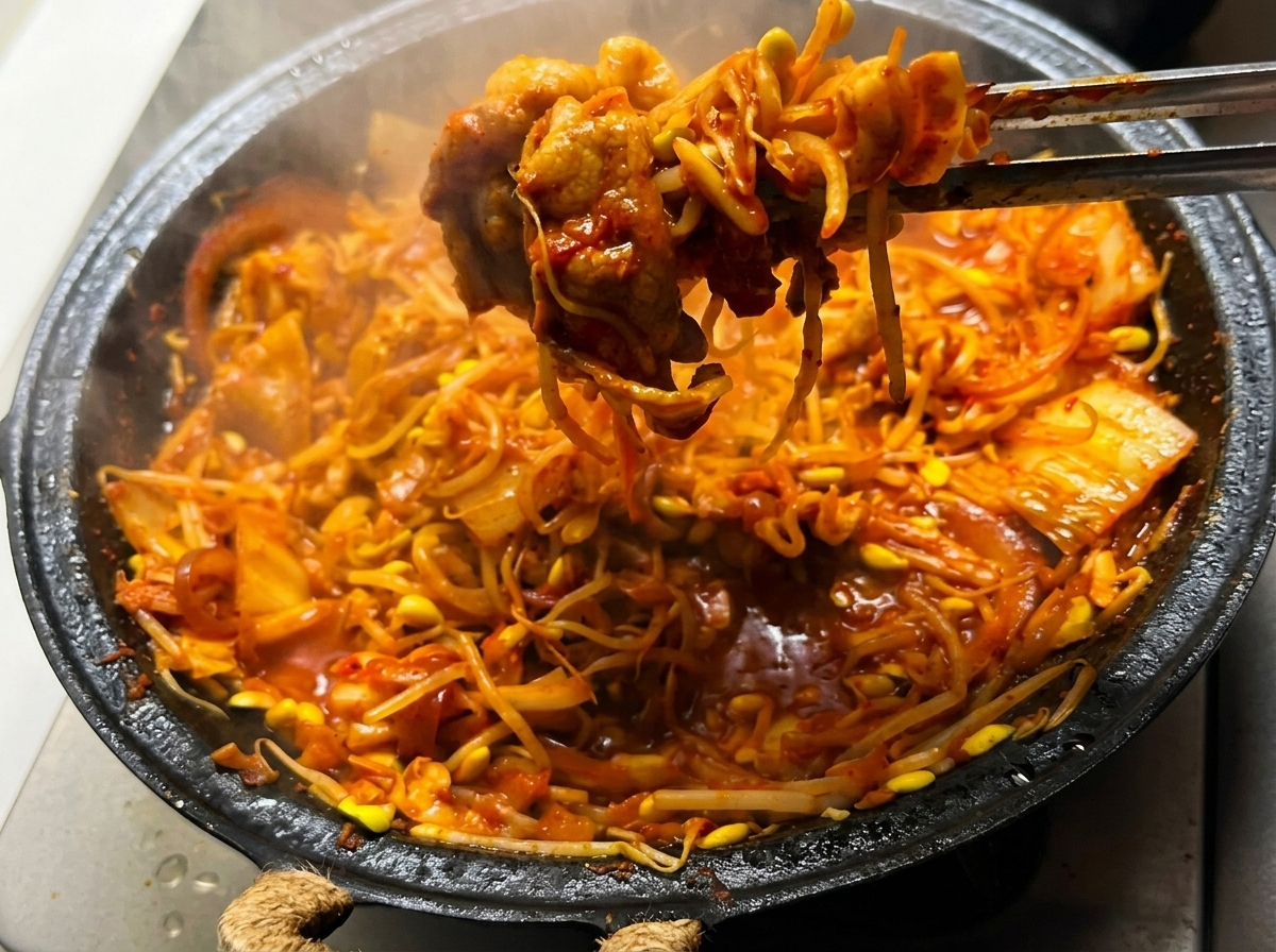 Die Mischung aus Schweinebauch, Kimchi und Sojasprossen wird in der Pfanne über einer hohen Flamme geschwenkt.