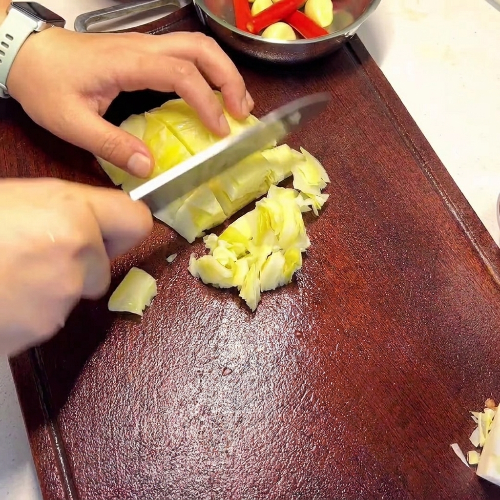 Hände halten ein Messer und schneiden hellgrünen, eingelegten Kohl auf einem dunklen Holzschneidebrett.