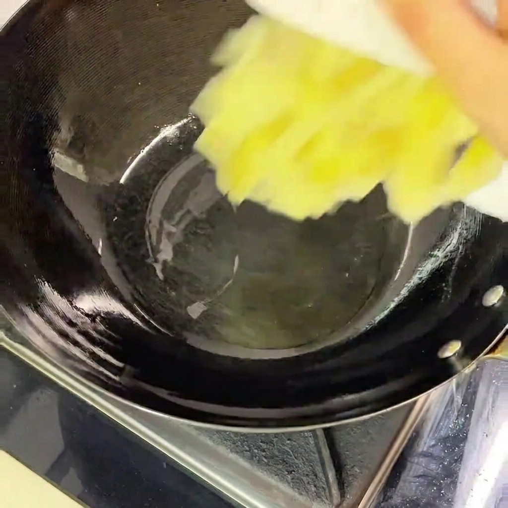Geschnittener eingelegter Kohl wird von einem weißen Teller in einen heißen, schwarzen Wok mit etwas Öl gegeben.