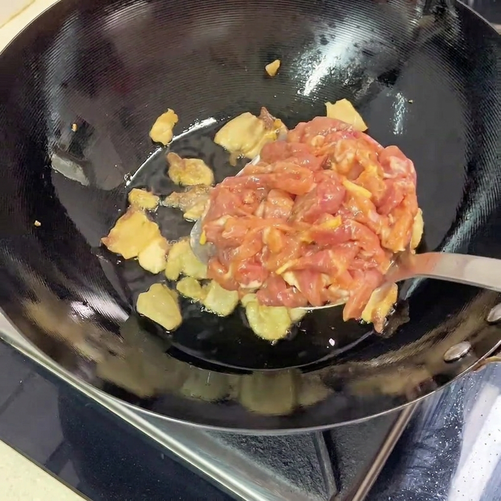 Marinierte magere Schweinefleischstreifen werden zum ausgelassenen Schweinebauch in den heißen Wok gegeben.