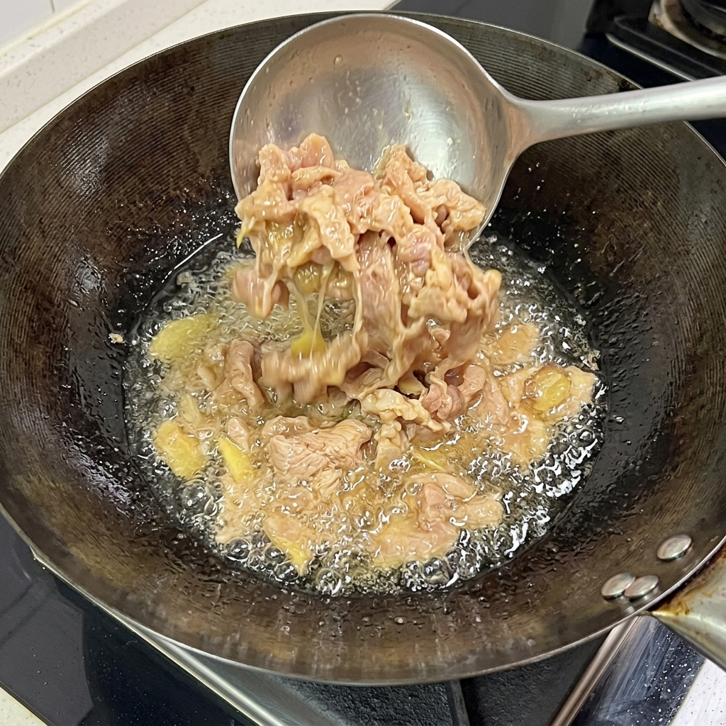Schweinefleischscheiben braten im Wok und zeigen eine gegarte, gebräunte Oberfläche.