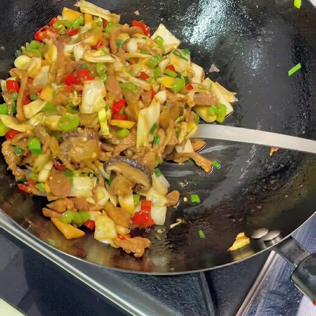 Ein Metallspatel hebt eine farbenfrohe Mischung aus gebratenem, eingelegtem Kohl, Schweinefleisch und Paprika aus dem schwarzen Wok auf einen Teller.