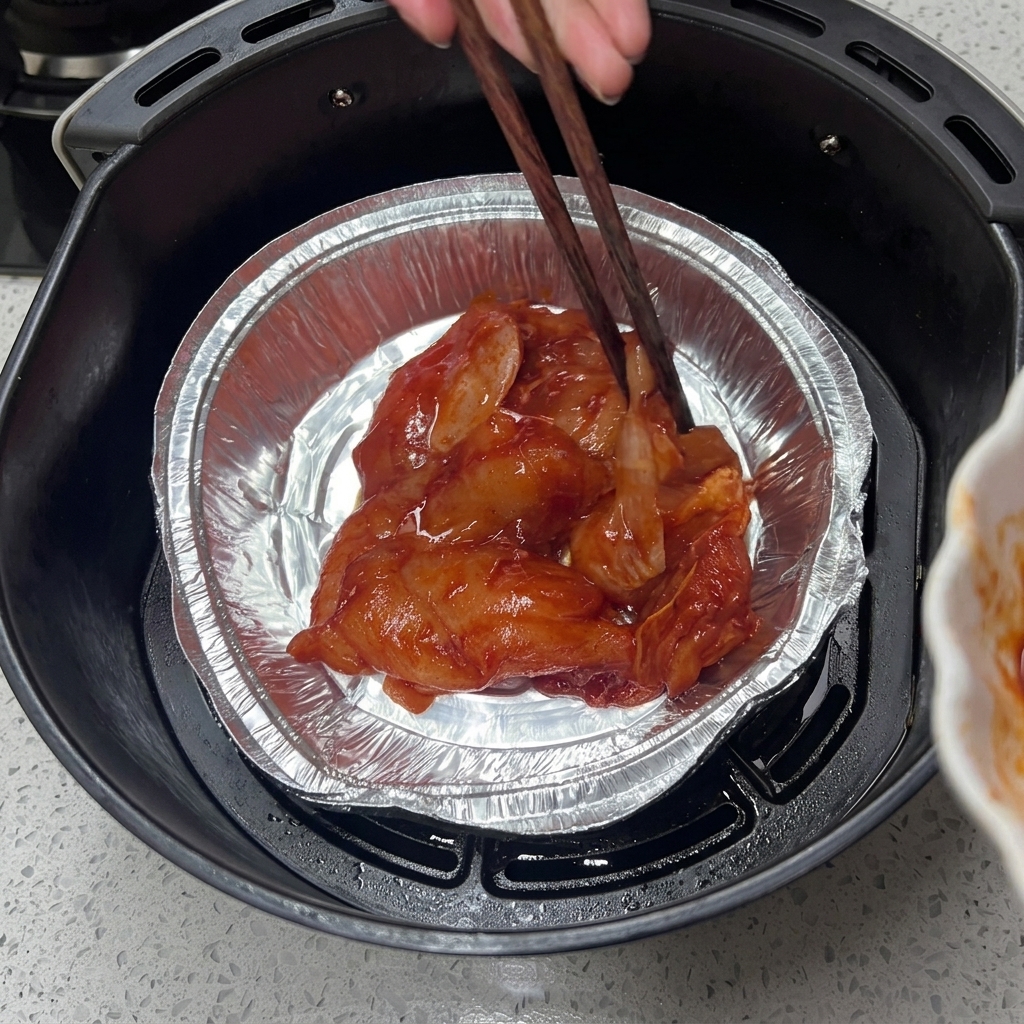 Mariniertes Hähnchen in einer Aluschale für die Heißluftfritteuse.