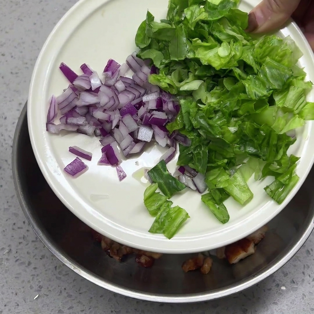 Gehackte rote Zwiebeln und Salat werden über den Reis gegeben.