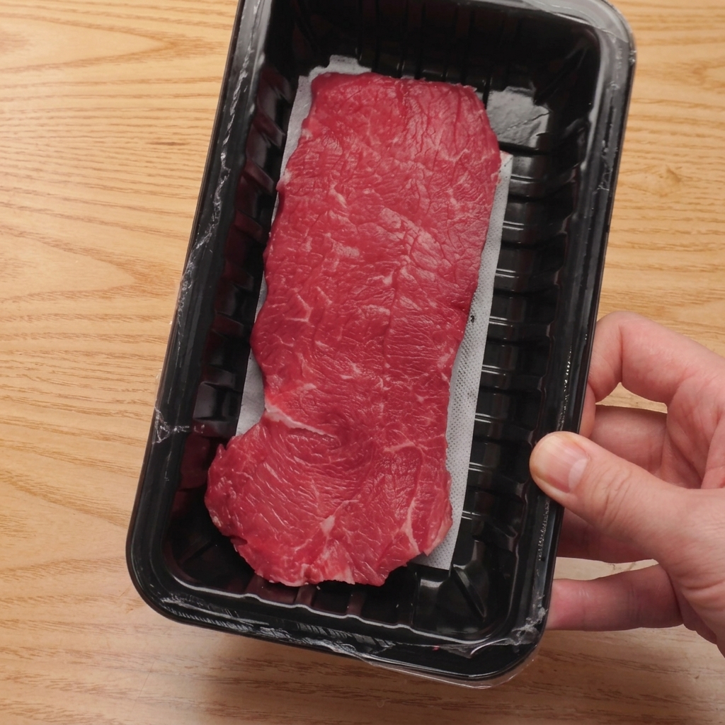 Rohes Rinderfilet wird auf einem Holzbrett in gleichmäßige Würfel geschnitten.