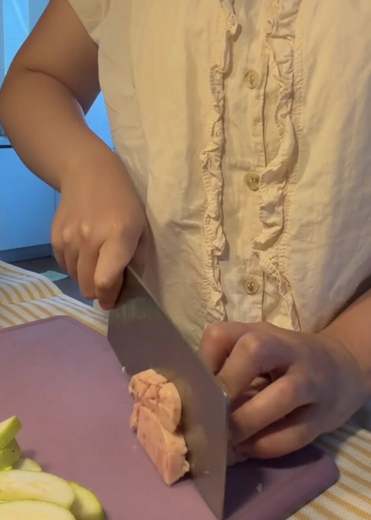 Frühstücksfleisch wird auf einem lilafarbenen Schneidebrett in kleine, gleichmäßige Würfel geschnitten.
