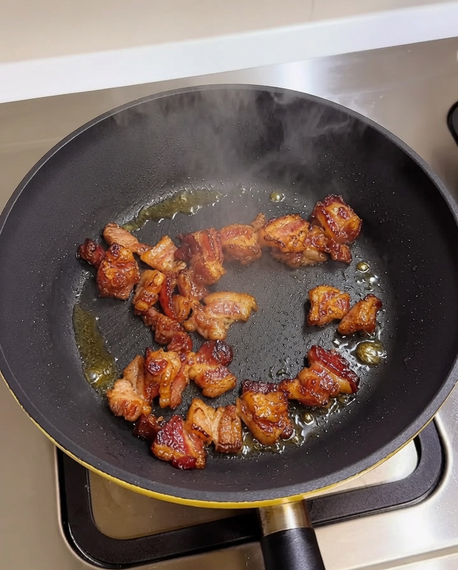 Stücke von Schweinebauch bräunen in einer heißen Pfanne.