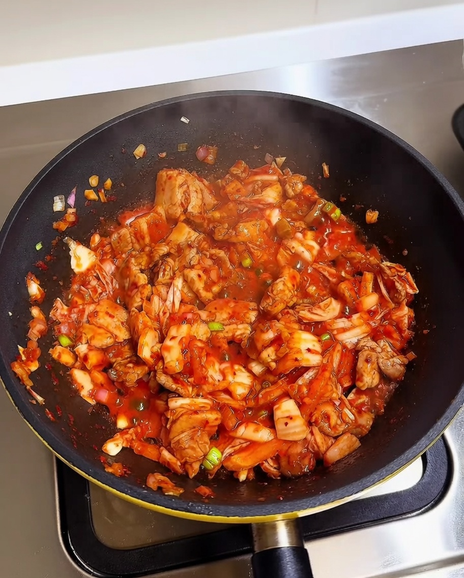 Gekochter weißer Reis wird in eine Pfanne mit gebratenem Kimchi und Schweinebauch gegeben.