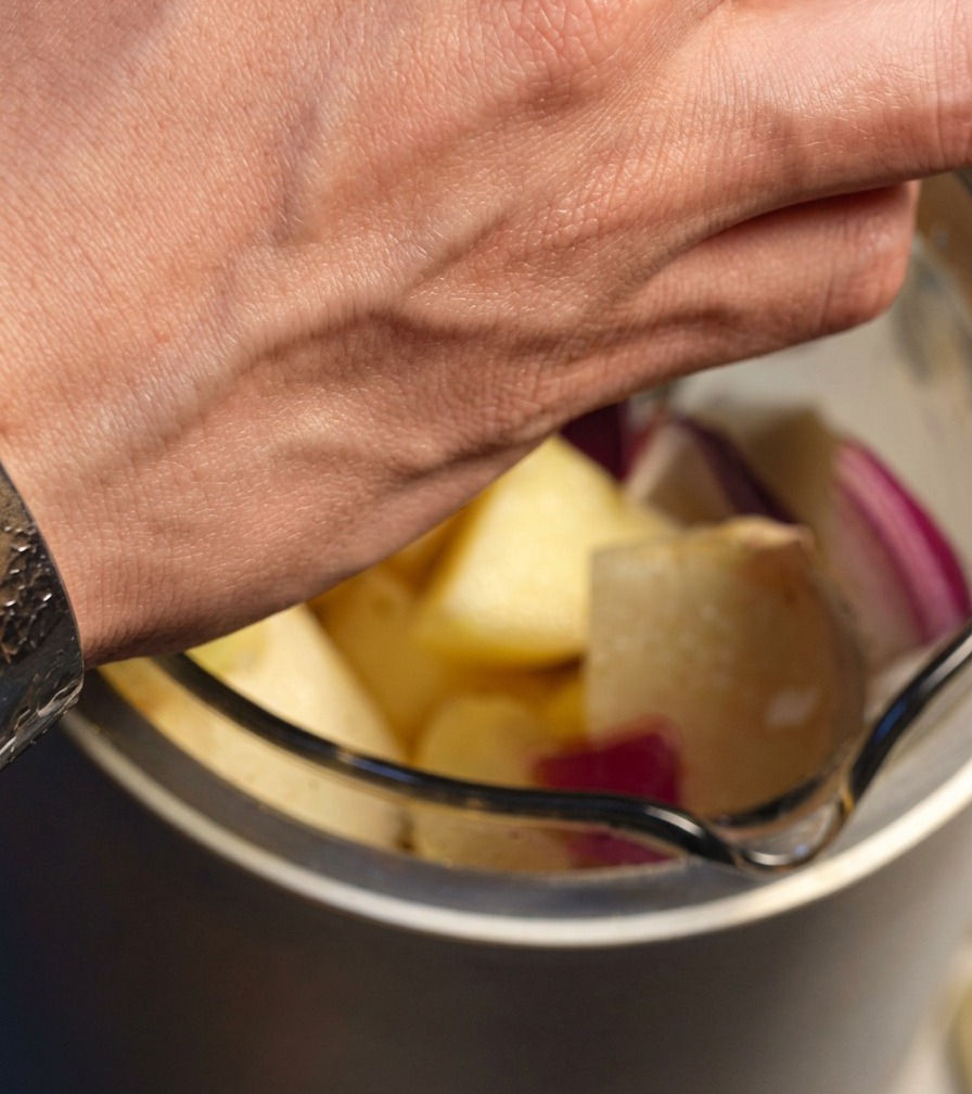 Rote Zwiebel, Apfel, Birne und Knoblauchstücke werden in einen Mixer gegeben.