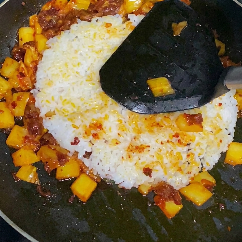 Der fertige Kimchi-Reis wird in der Pfanne umgerührt.