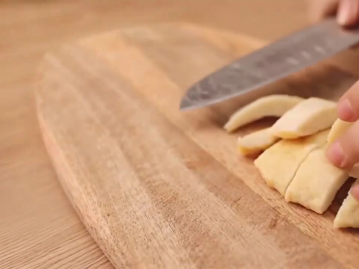 Nahaufnahme eines Messers, das einen I-förmigen Schnitt in ein vegetarisches Würstchen macht.