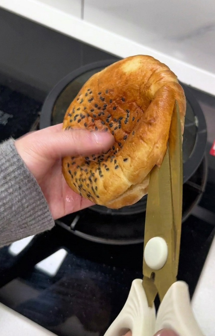 Ein Burger-Bun wird vorsichtig mit einer Schere aufgeschnitten.