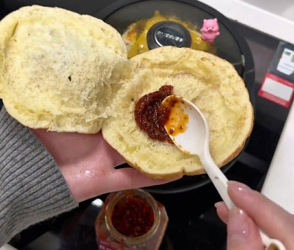 Chilisauce wird auf der Innenseite des Brötchens verstrichen.
