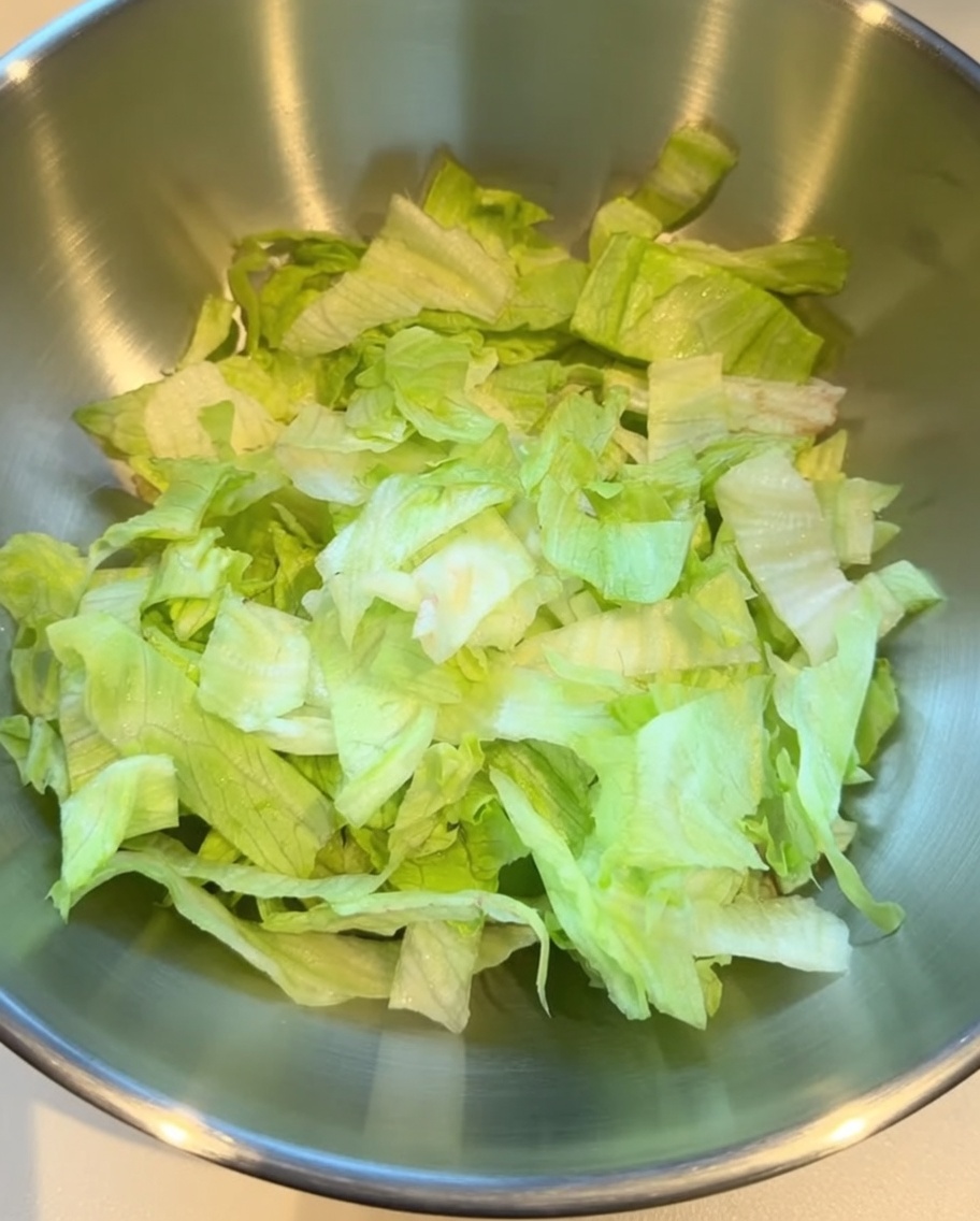 Frisch geschnittener Salat in einer großen Edelstahlschüssel.
