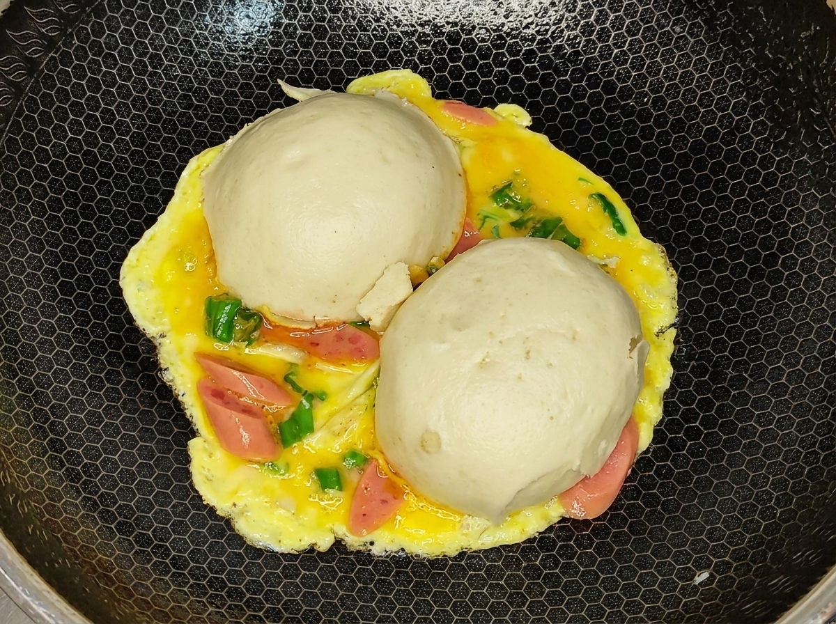 Das gewendete Omelett mit den Brötchenhälften nach unten im Wok.