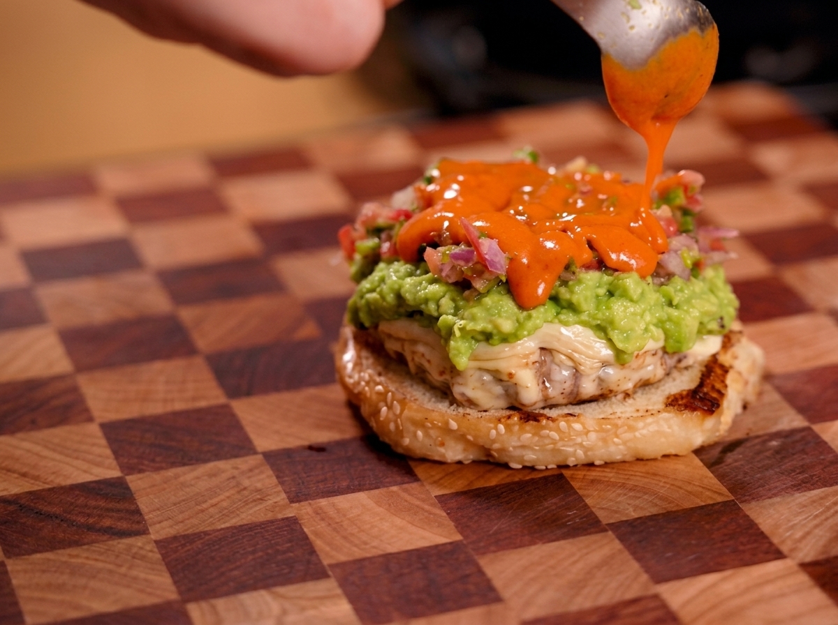 Helle orangefarbene scharfe Sauce wird über die Salsa-Schicht geträufelt.