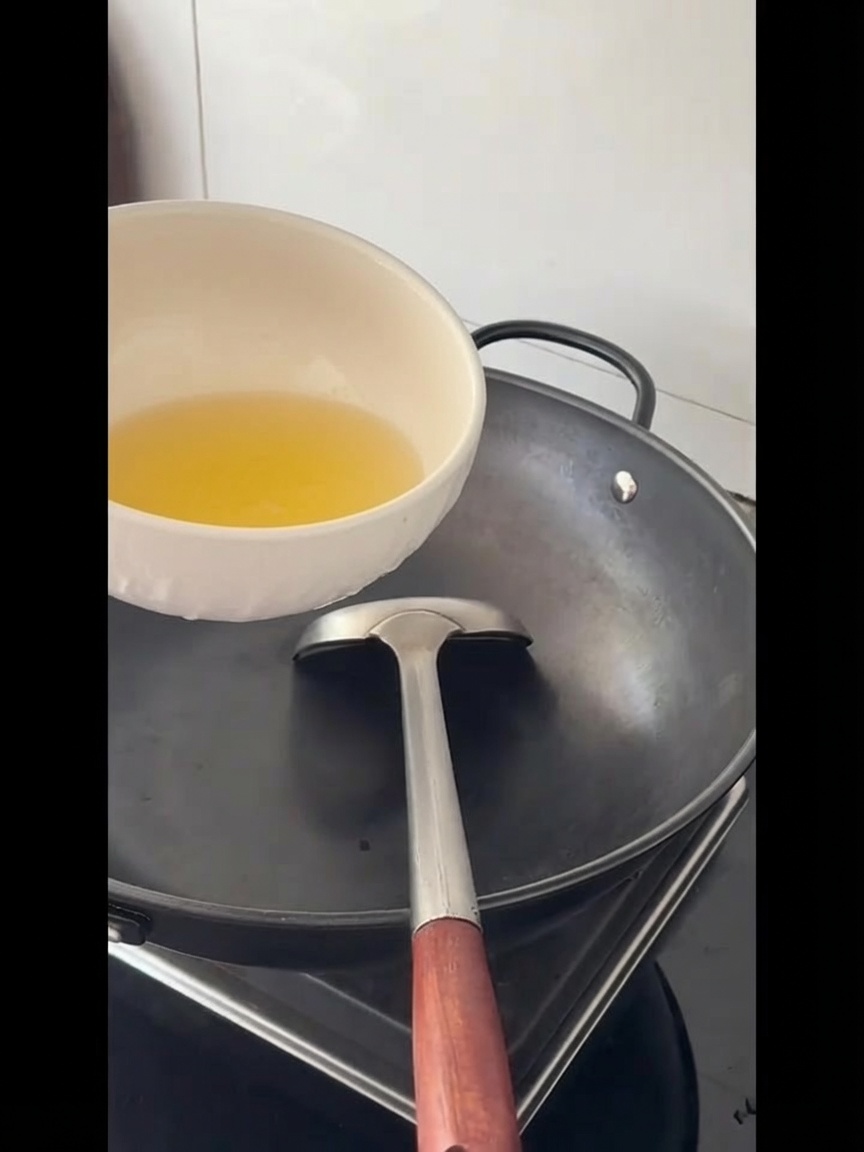 Speiseöl wird in einen großen leeren Wok gegossen.