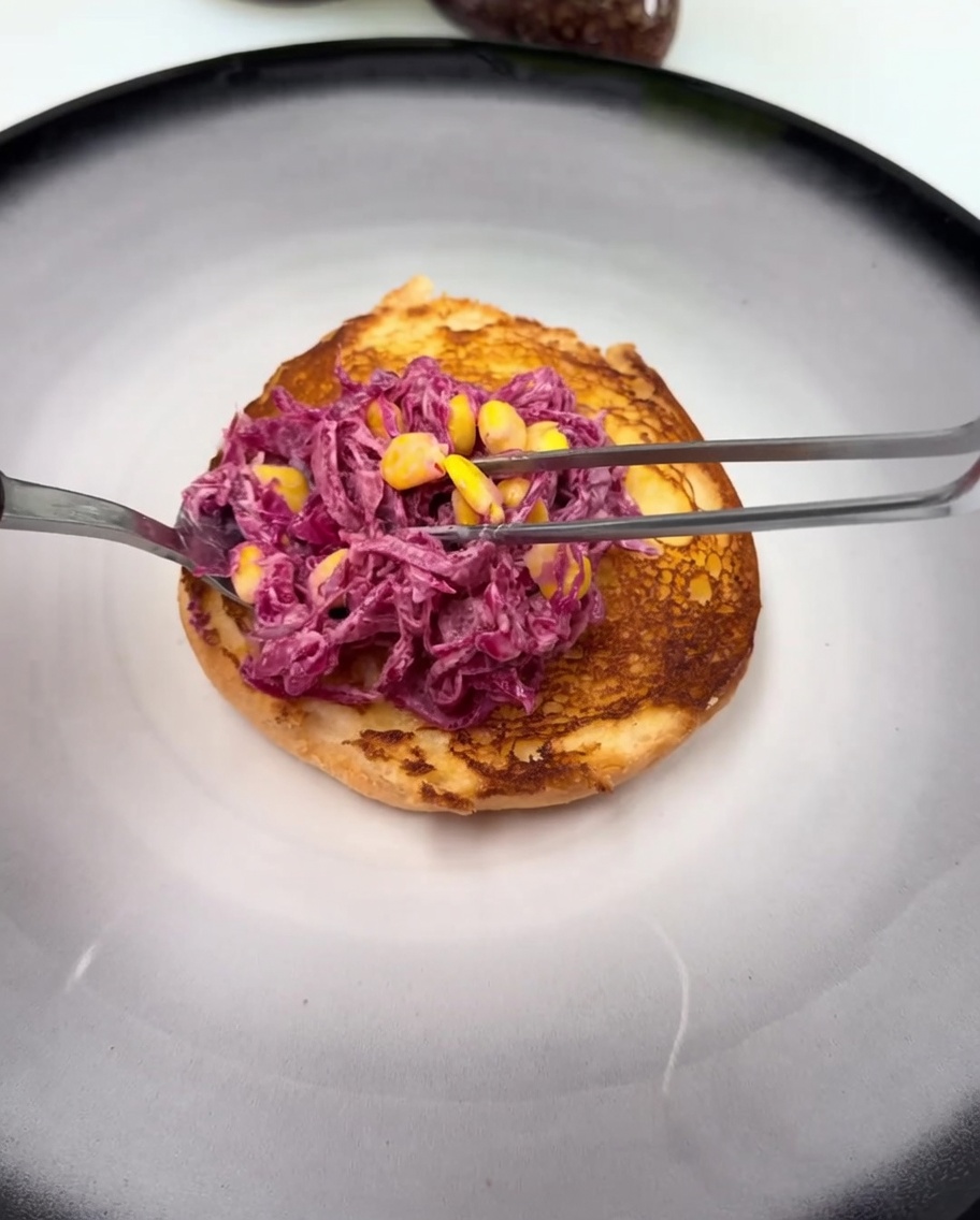 Die untere getoastete Burgerhälfte mit einem Klecks Sauce und dem Rotkohl-Mais-Salat.