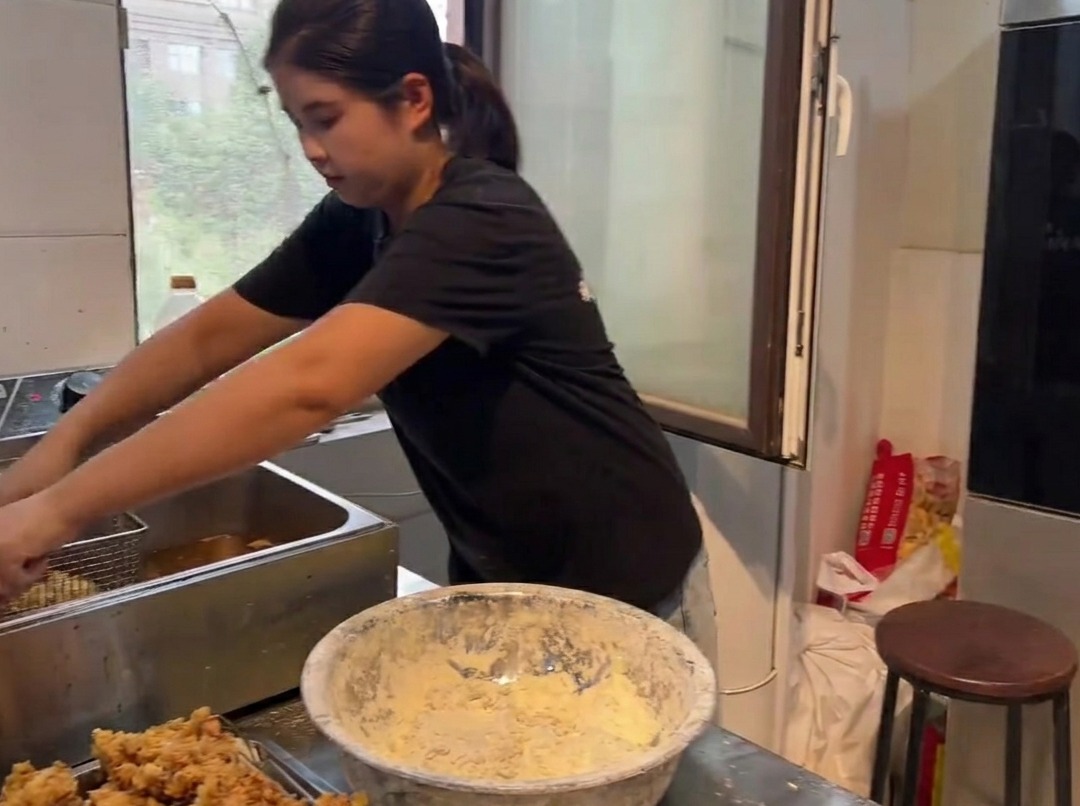 Goldbraune, knusprige Hähnchenstücke werden aus einer Fritteuse gehoben.