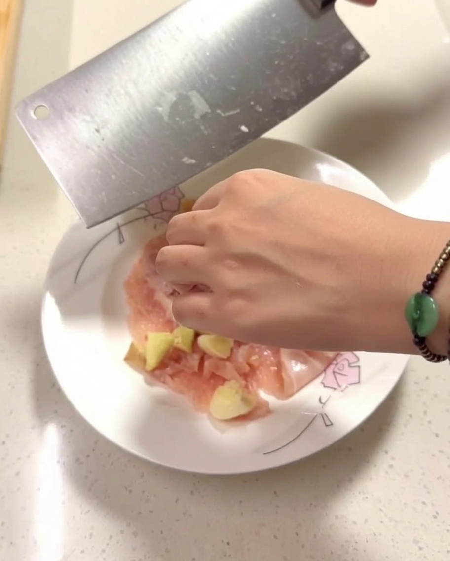 Rohe Hähnchenstücke auf einem Teller, gewürzt mit Ingwer, Knoblauch und Gewürzen.