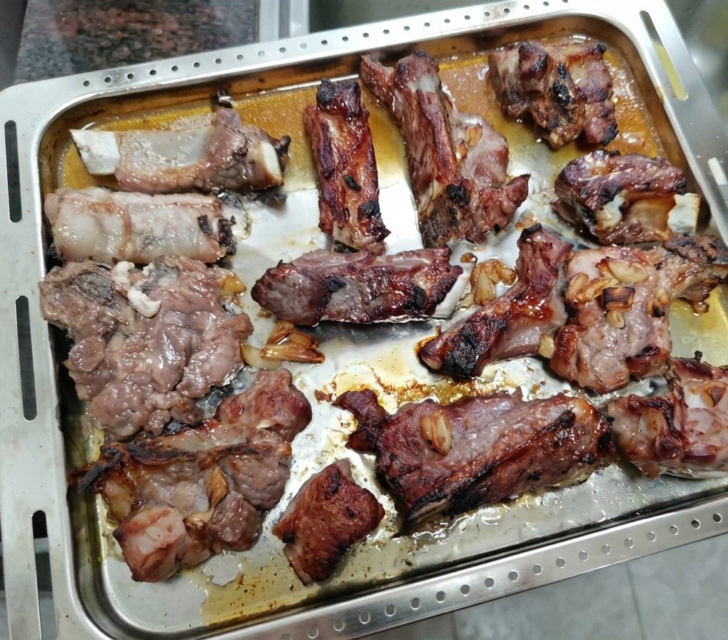 Teilweise gebratene Rippchen auf einem Blech, bereit zum Bestreichen mit Honig.
