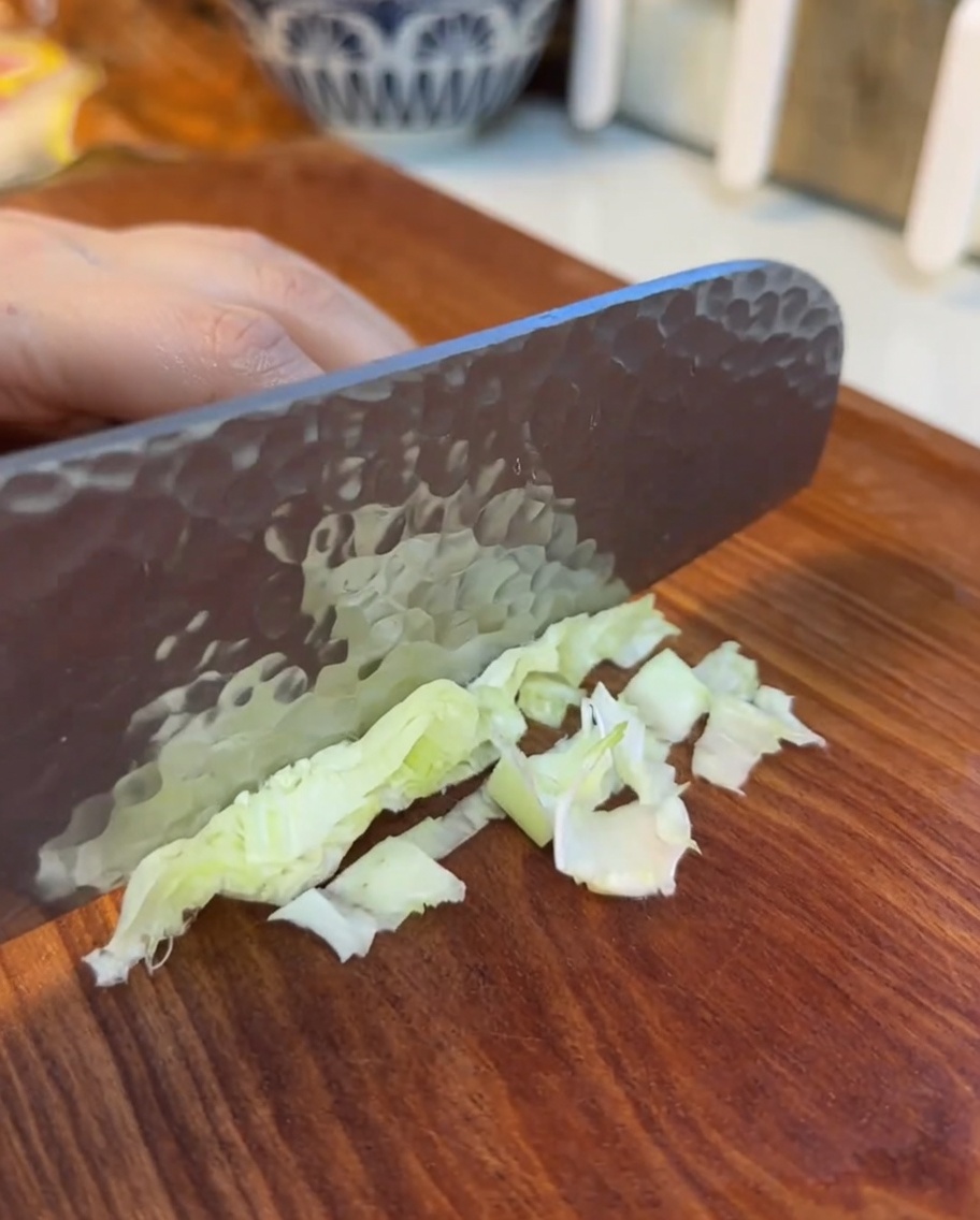 Fein geschnittene Salatblätter auf einem Holzschneidebrett.
