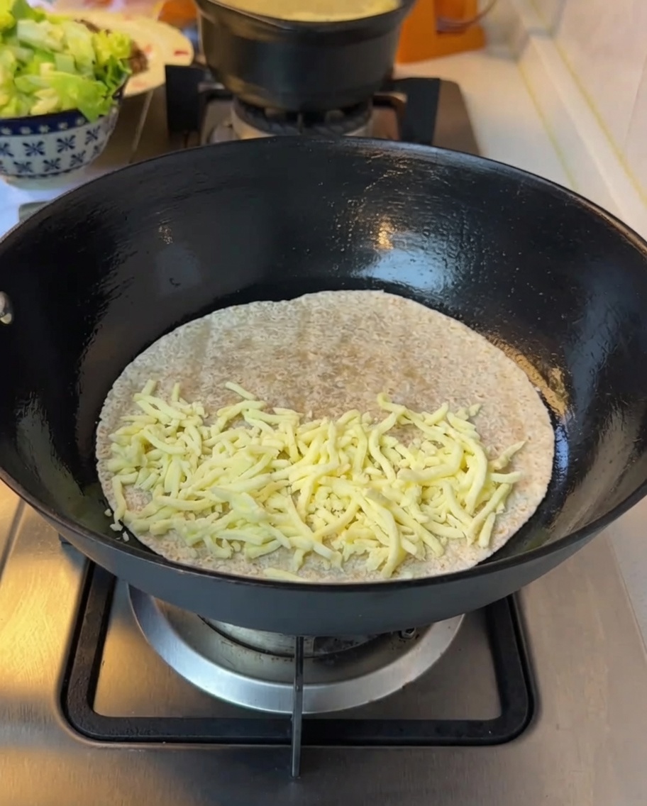 Fein gehackter Salat wird auf den geschmolzenen Käse der Tortilla gegeben.