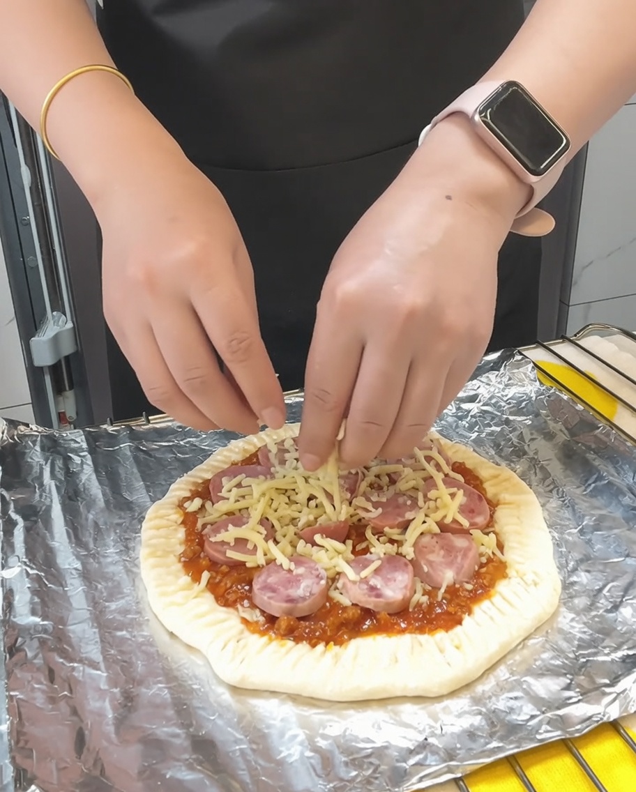 Letzte Handvoll Mozzarella wird über die Pizza gestreut, gefolgt von einer Prise getrockneter Petersilie.