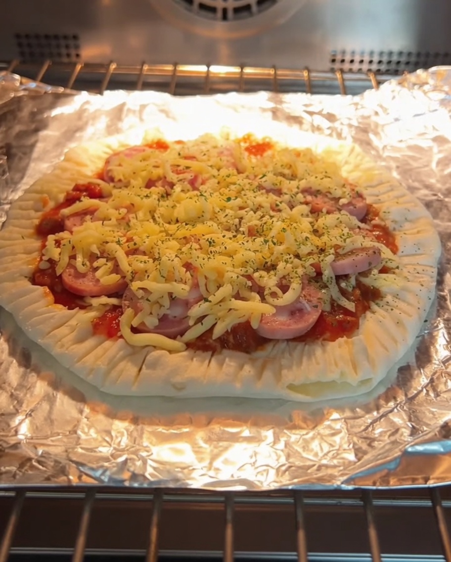 Eine frisch gebackene Frühlingszwiebel-Pfannkuchen-Pizza mit geschmolzenem Käse und Wurstscheiben auf einem Backrost.