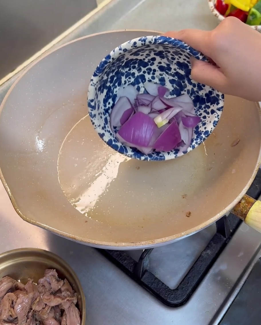 Rote Zwiebelstücke werden in einer leicht geölten Pfanne angebraten.
