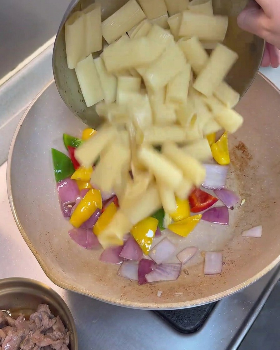 Gekochte Rigatoni werden zu den gebratenen Paprika und Zwiebeln in die Pfanne gegeben.