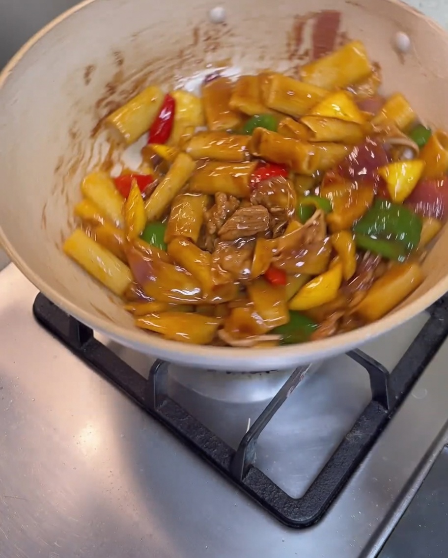 Rigatoni, Fleisch und Gemüse werden in der Pfanne vermengt, bis sie mit einer glänzenden braunen Sauce überzogen sind.