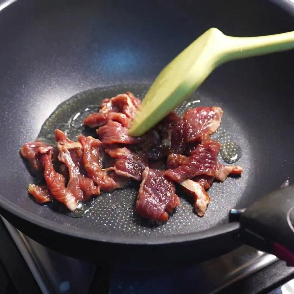 Rindfleischstreifen werden in einer heißen Pfanne braun gebraten.