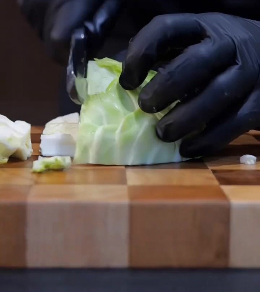 Frischer Kohl wird auf einem Holzbrett in mundgerechte Stücke gehackt.