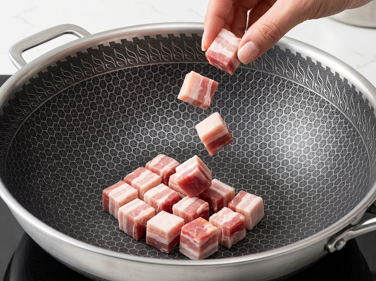 Speckstücke braten in einer Pfanne goldbraun in ihrem eigenen Fett.