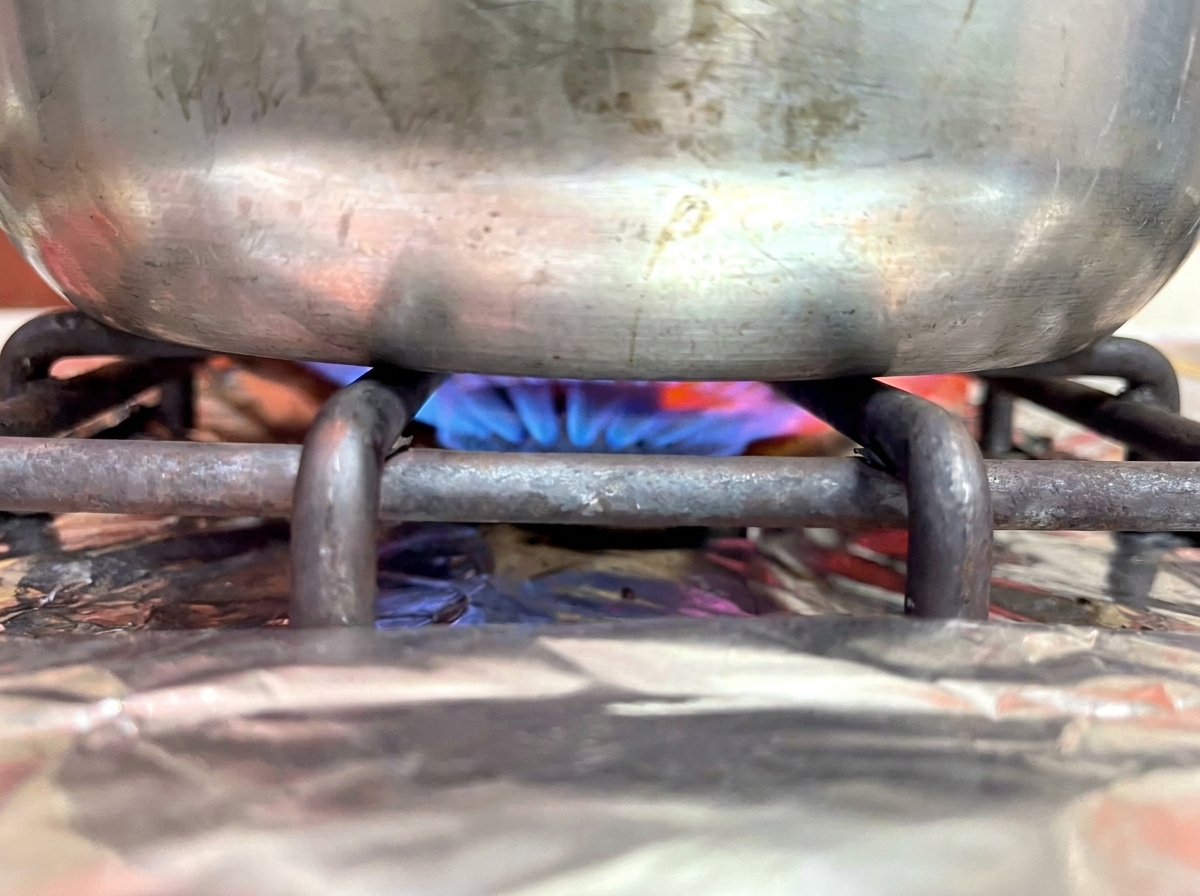 Der Topf steht auf dem Herd über einer blauen Gasflamme.