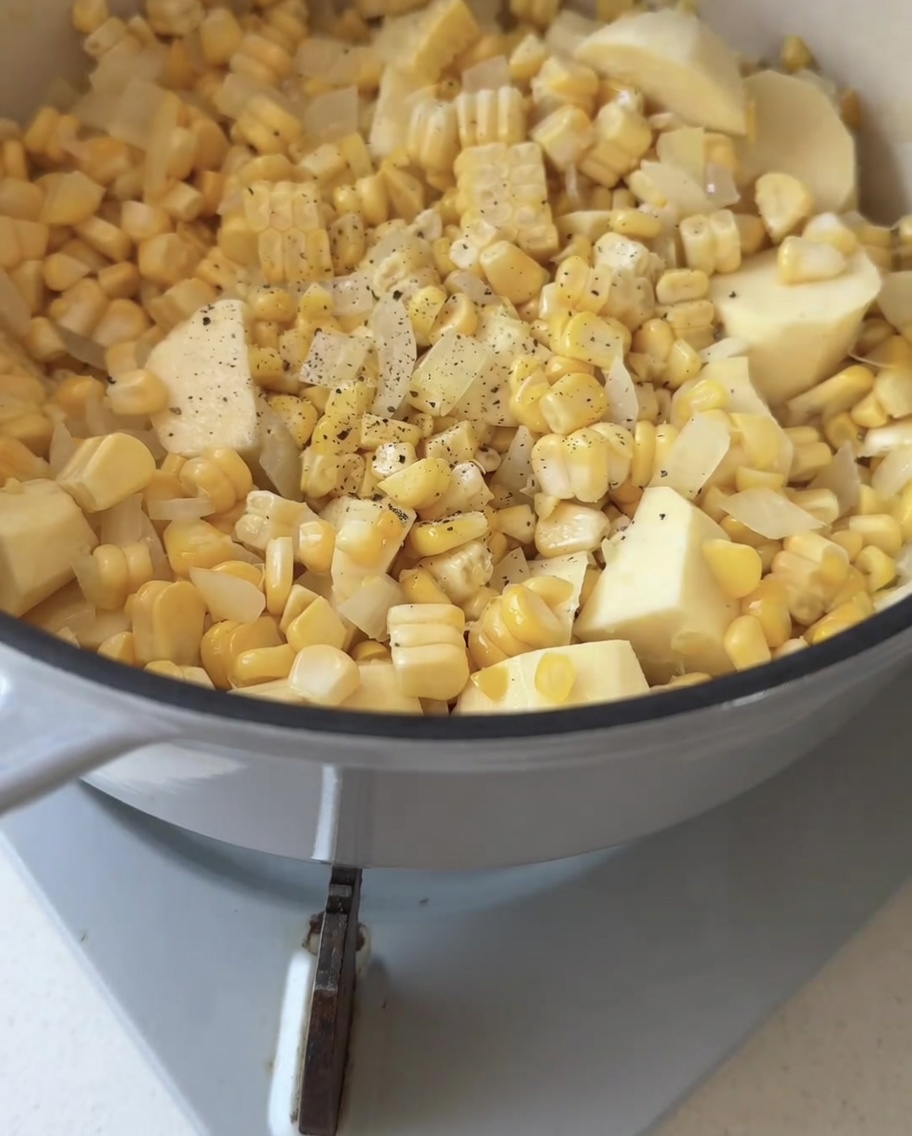Schwarzer Pfeffer wird frisch über eine Mischung aus Mais, Zwiebel und Süßkartoffel gemahlen.