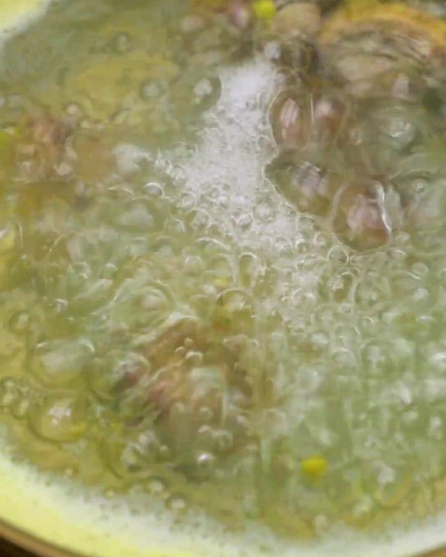 Muscheln werden mit einem Sieb in einen Topf mit kochendem Maiswasser gegeben.
