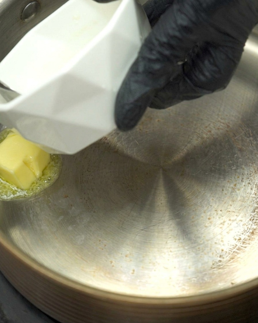 Geschmolzene Butter in einem Topf mit gehacktem Knoblauch und Mehl, das gerade angeschwitzt wird.