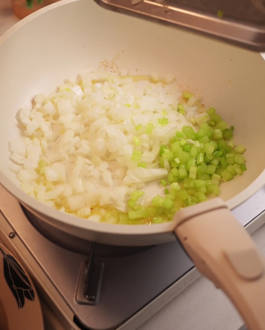 Gehackte Zwiebeln und Sellerie werden in einer Pfanne angedünstet.