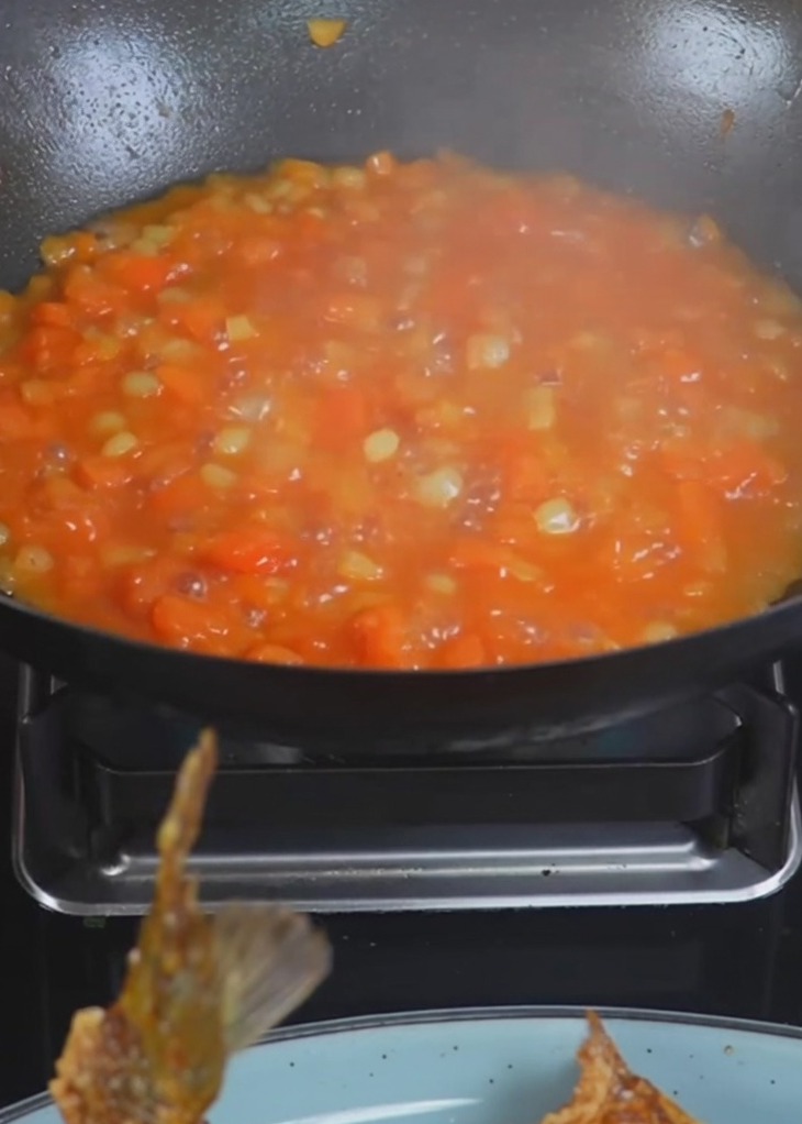 Kochendes Wasser wird in einen Wok mit gebratenen Kartoffeln und Tomaten gegossen.