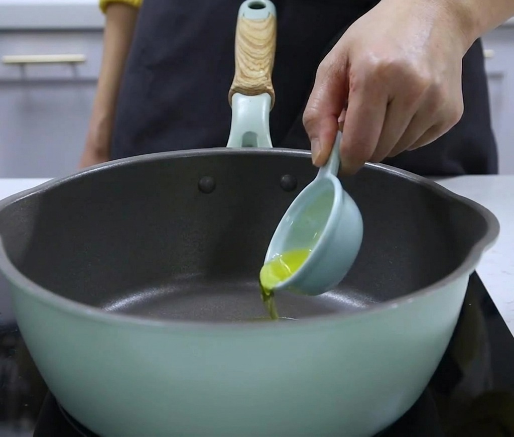 Walnussöl wird aus einem kleinen Messlöffel in einen Topf gegeben.