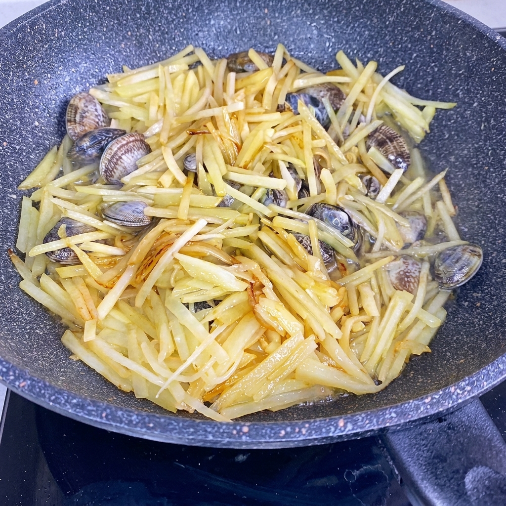 Wasser wird in einen Wok mit gebratenen Kartoffelstreifen und frischen Muscheln gegossen.