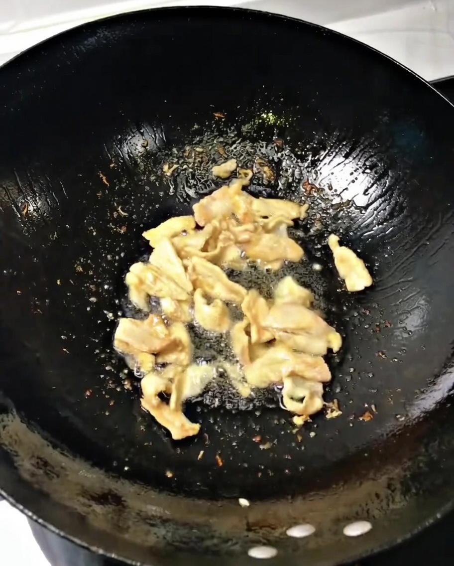 Gehackte Frühlingszwiebeln und Ingwer werden in den heißen Wok zum Fleisch gegeben.