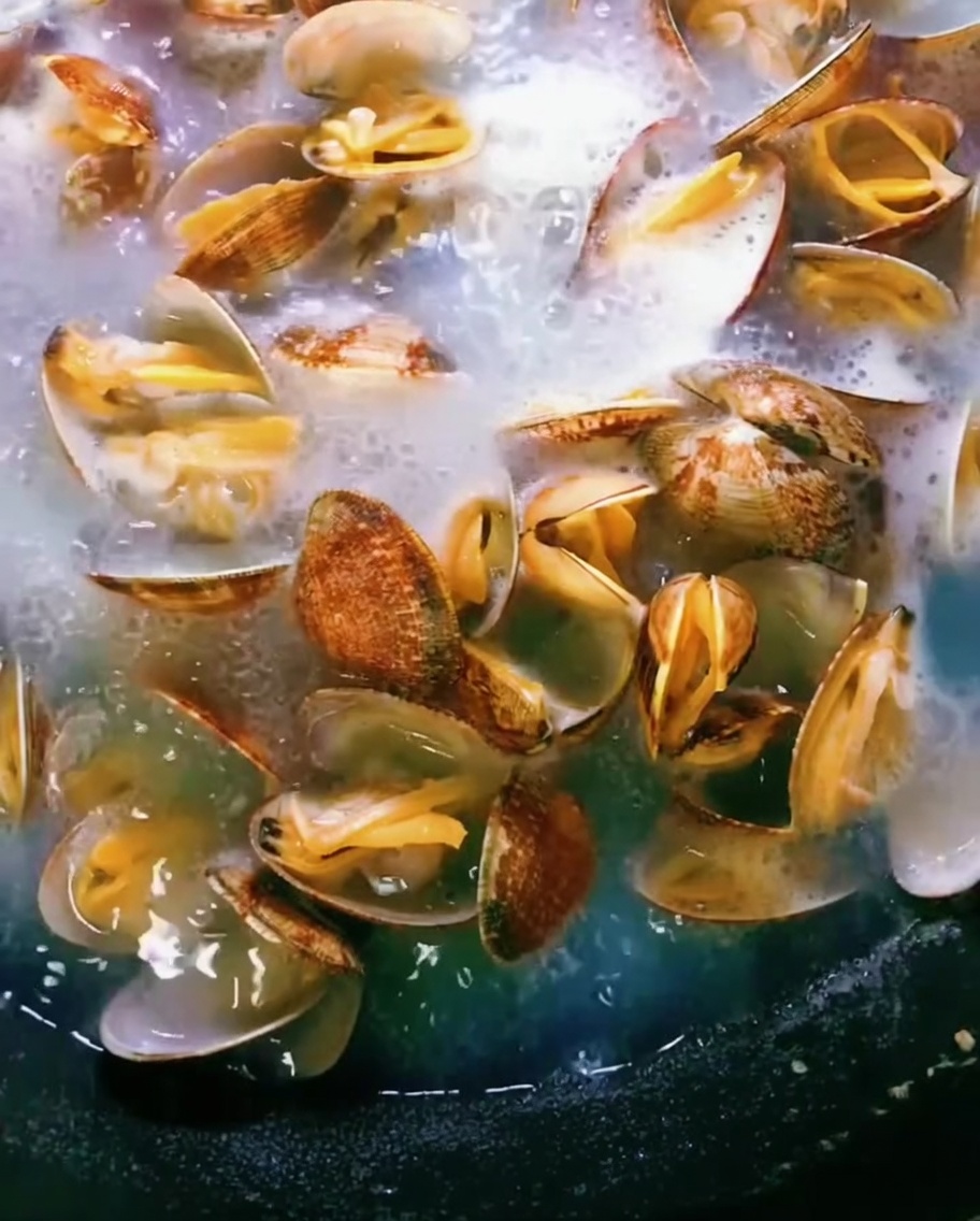 Muscheln in einem Topf mit kochendem Wasser, die Schalen öffnen sich.