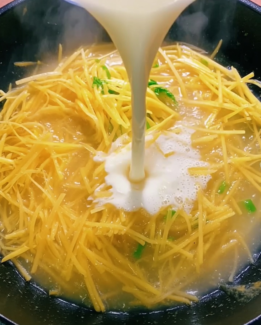 Klare Flüssigkeit wird aus einer Schüssel in den Wok gegossen.