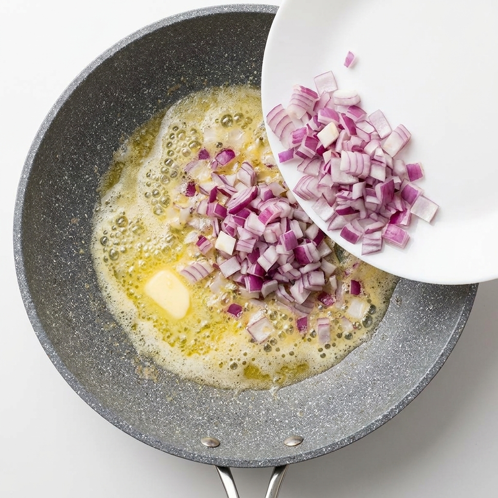 Gewürfelte rote Zwiebeln werden in eine Pfanne mit geschmolzener Butter gegeben.