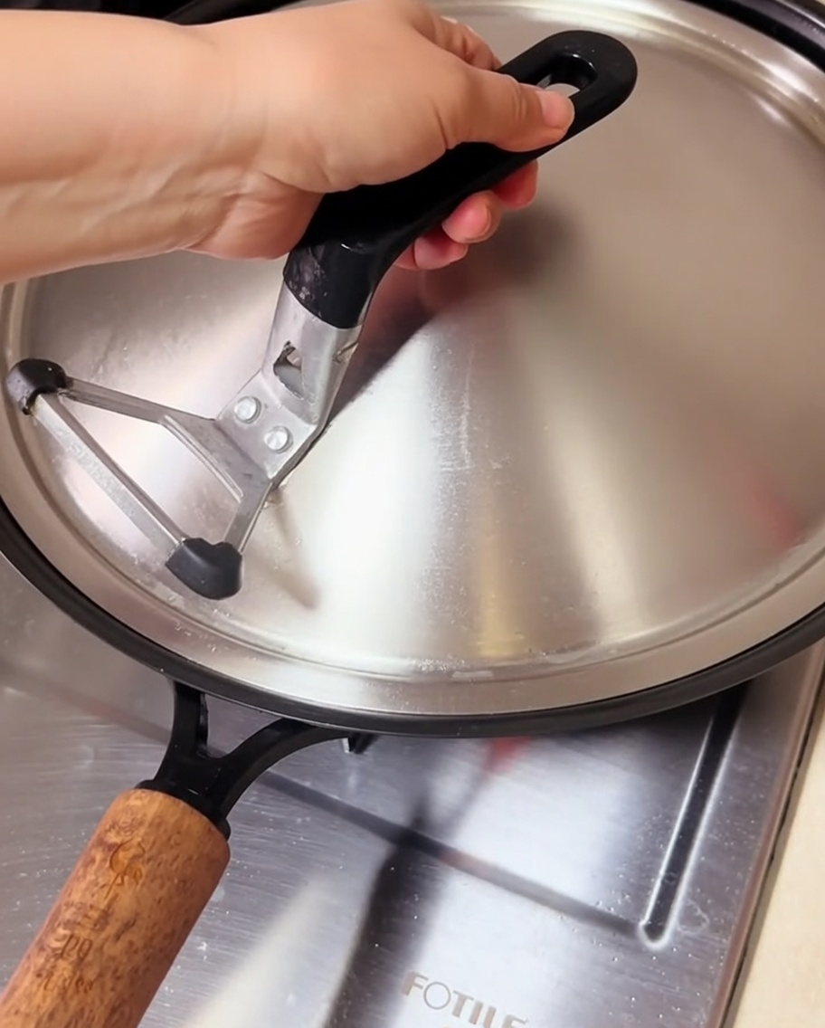 Muscheln kochen in einem abgedeckten Wok, Dampf entweicht unter dem Deckel.